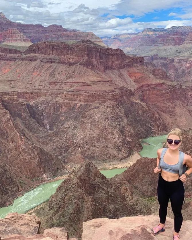 Advisor posing on a cliff with a valley below and a rushing river. 