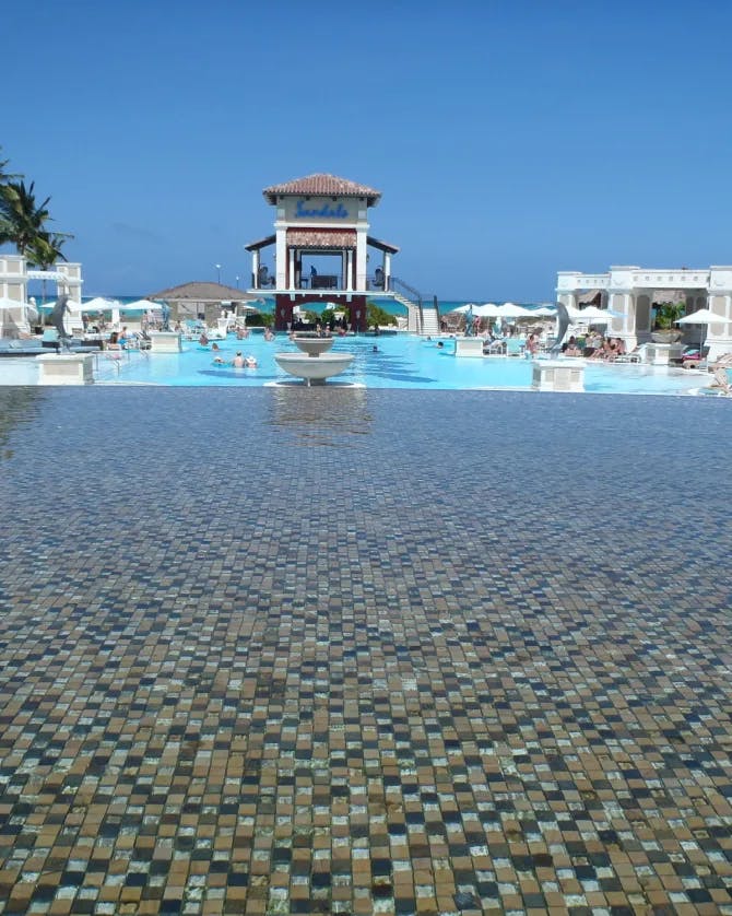A white-and-tan building overlooking a tile-floored pool