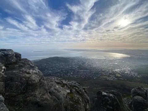 The image offers a scenic perspective from an elevated point, capturing a landscape with clouds and a cityscape below, taken at an angle.