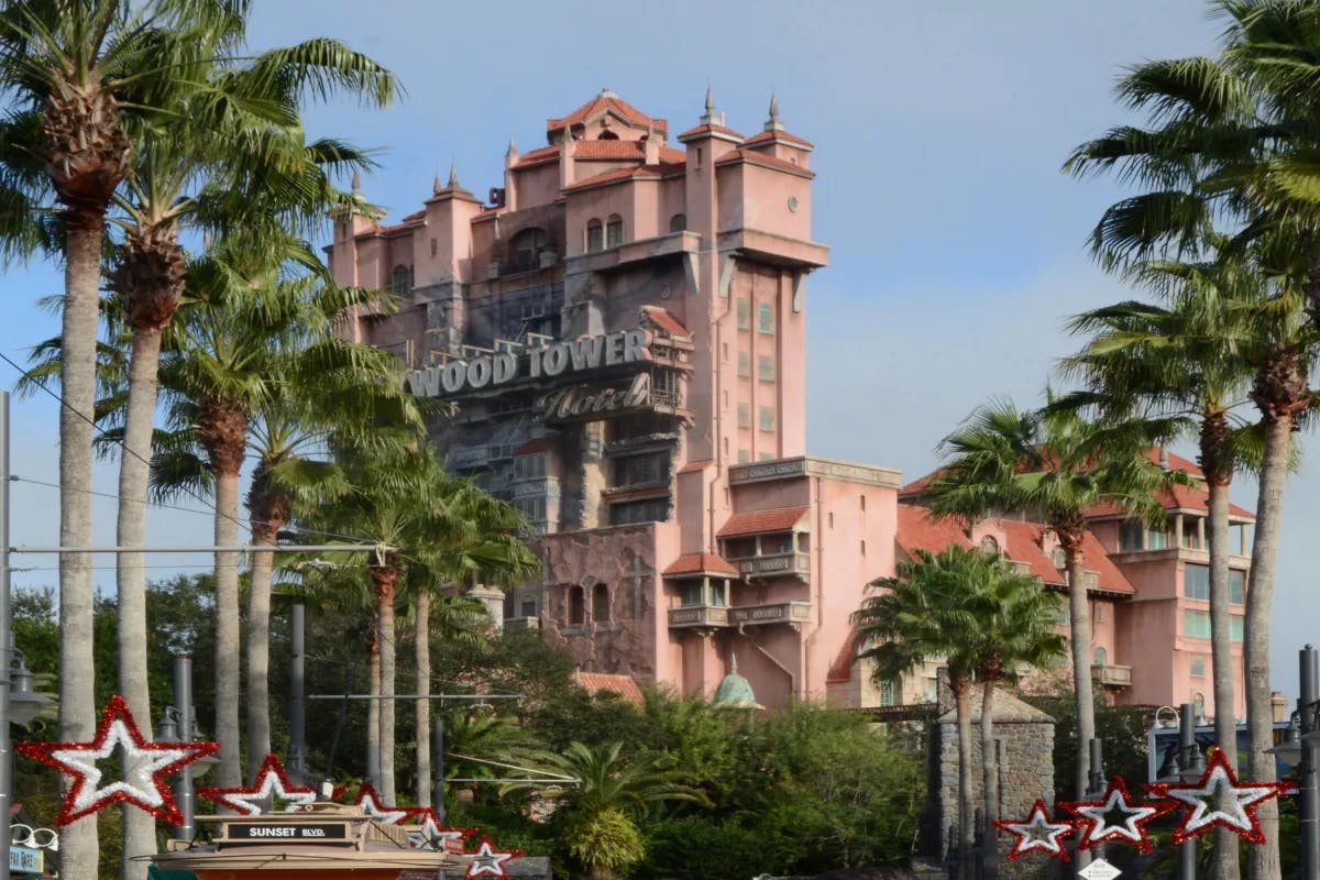 Tower of Terror ride from the outside – a tall pink building that says "Hollywood Tower Hotel" surrounded by palm trees.