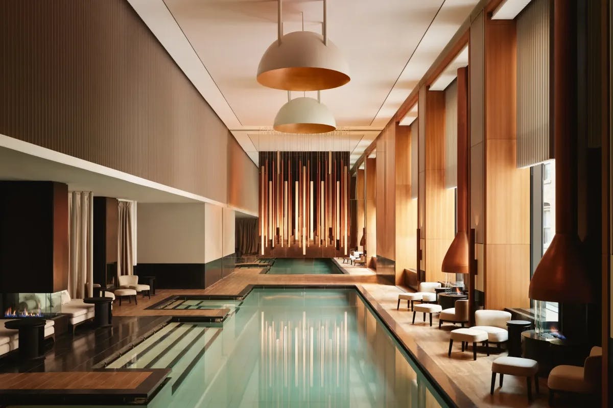 a luxe indoor pool in a room with towering windows and sleek wooden paneling