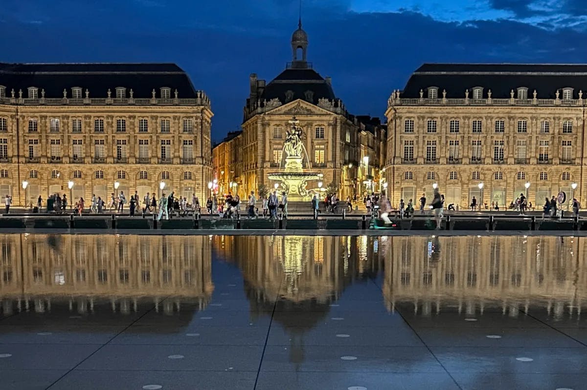 The image depicts an ancient stone gate with elaborate designs, juxtaposed against modern buildings, symbolizing a historical presence in a contemporary setting.