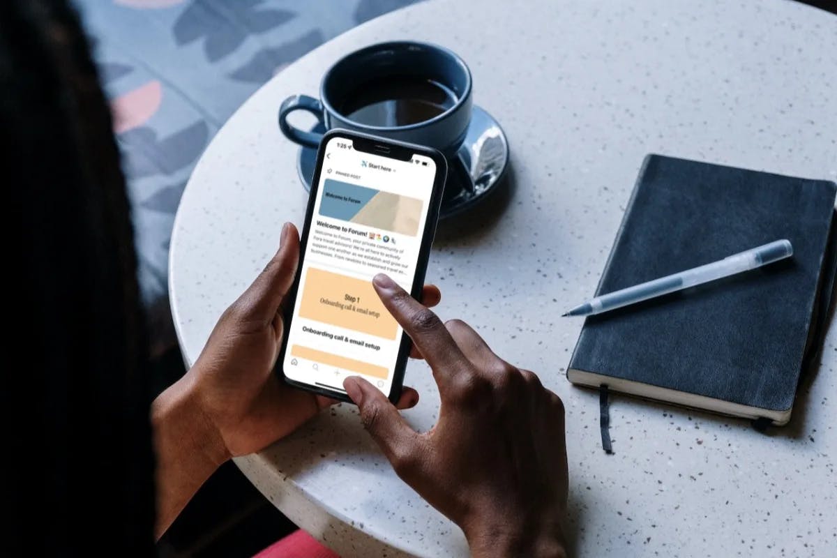 a table with a cup of coffee and a person's hands scrolling on a phone