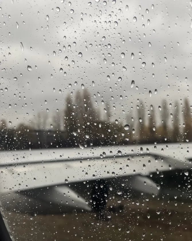 rain droplets on a plane window with a blurry city skyline in the background