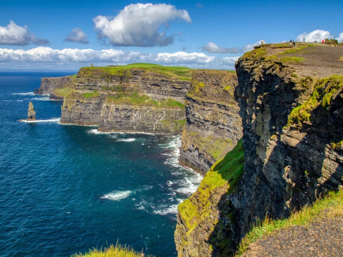 The Cliffs of Moher in Ireland, showcasing their dramatic drop into the Atlantic Ocean under a clear blue sky.