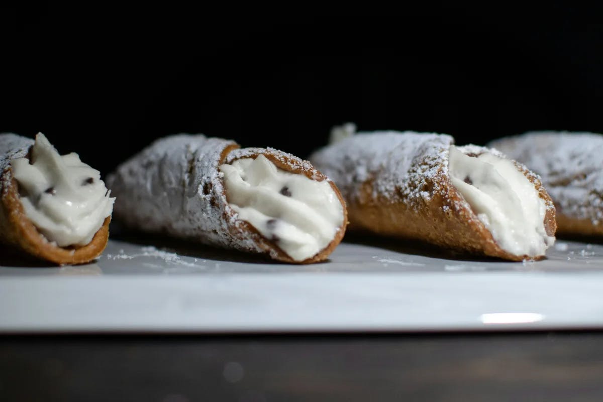 Cannoli with a golden-brown shell and creamy filling on a white plate.