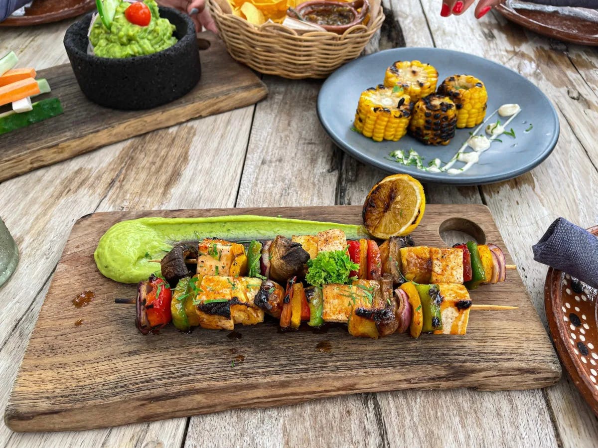 A picture of food platters served on a wooden table during daytime.