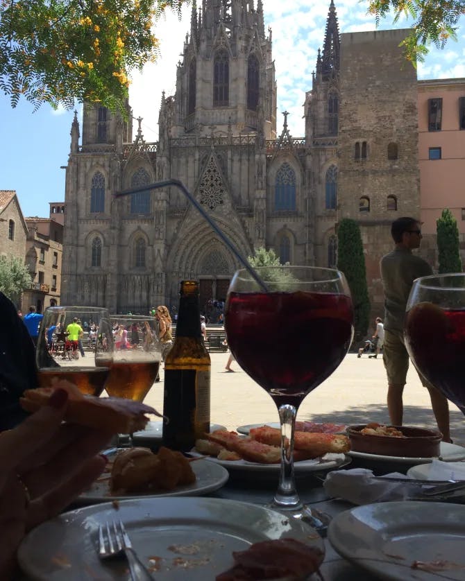 A drink on a table surrounded by plates with a church in the background outside. 