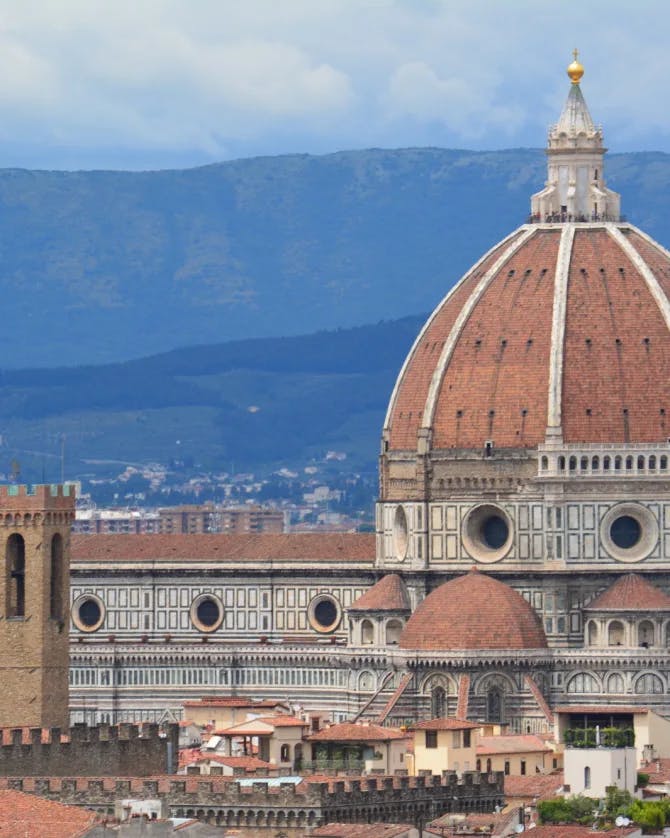 A brown building with dome in front of mountains. 