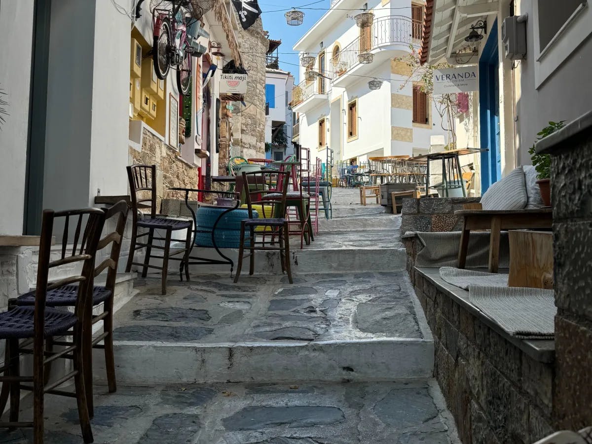 Street in town with shops, tables and chairs.