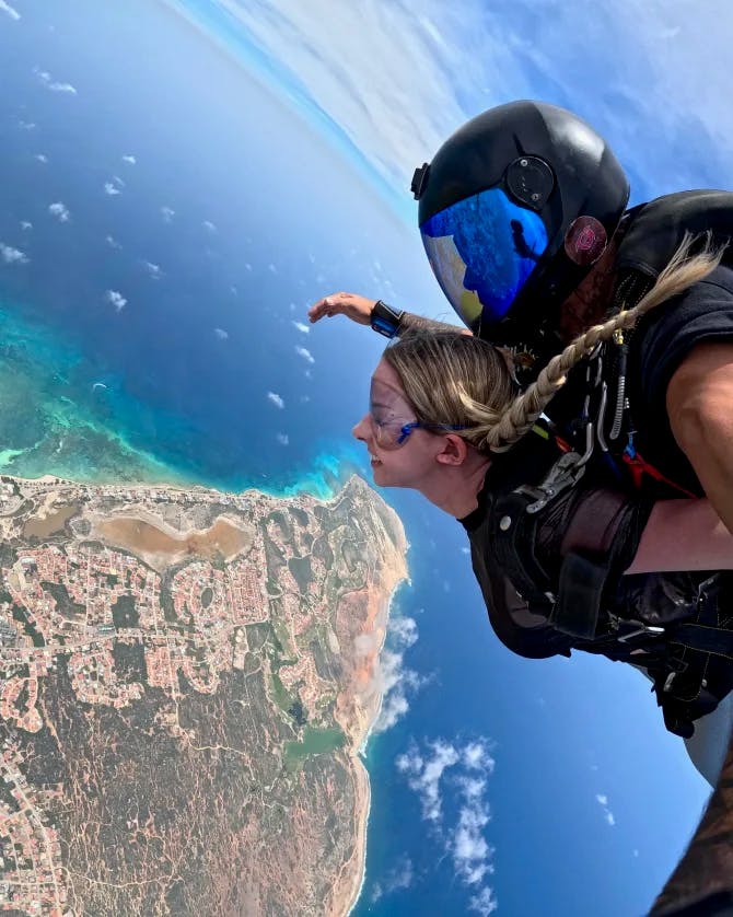 Travel advisor sky diving over a peninsula.