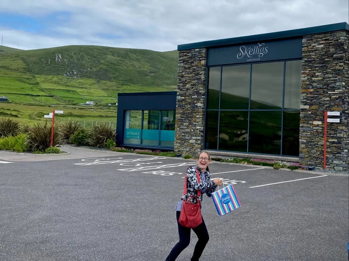 A woman with a bag standing in front of a building labelled as Skelligs.