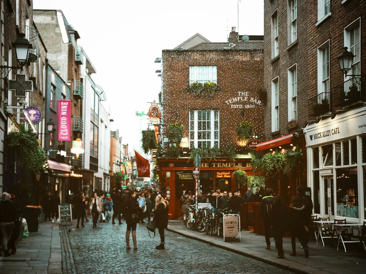 The image depicts a bustling street scene in the Temple Bar area of Dublin, known for its cultural atmosphere and nightlife.