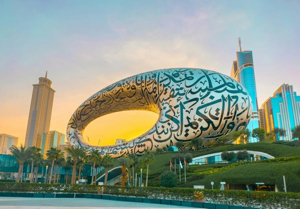 A large sculpture with calligraphy in front of a cityscape.