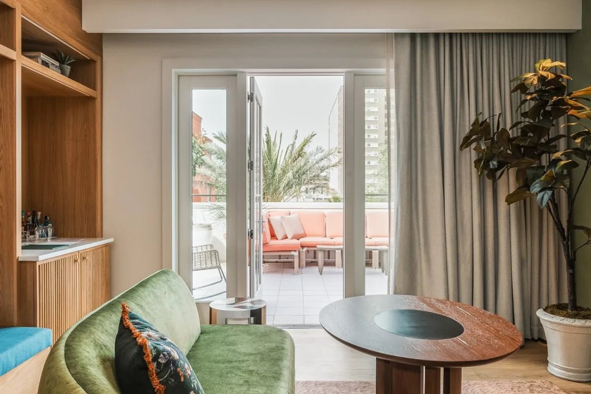 a green velvet couch in a suite overlooking an outdoor terrace