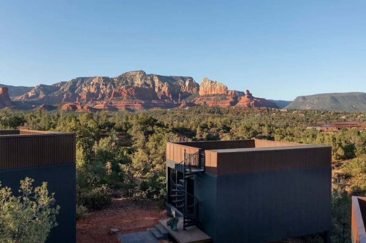 cube-shaped cabin in an Arizona landscape with red rocks in the distance