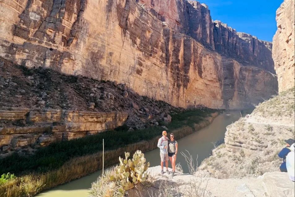 Couple posing for a photo next to a mountainside 