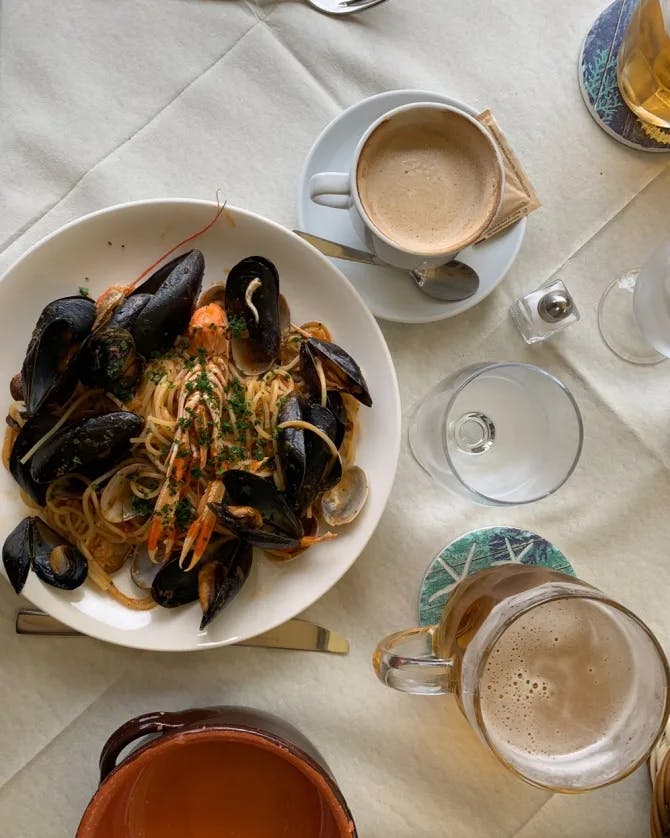 A table of spaghetti with oysters and coffee.