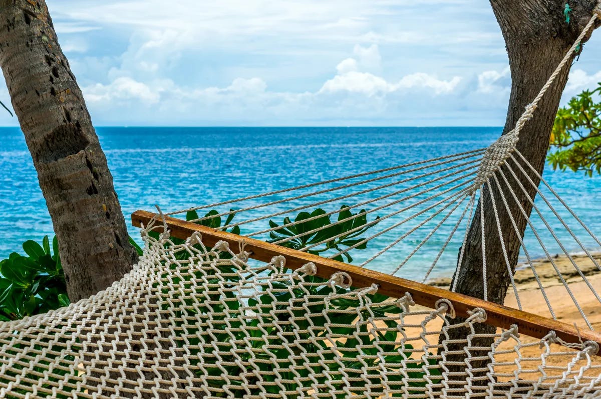 Hammock on the beach with the ocean in the distance on a sunny day.