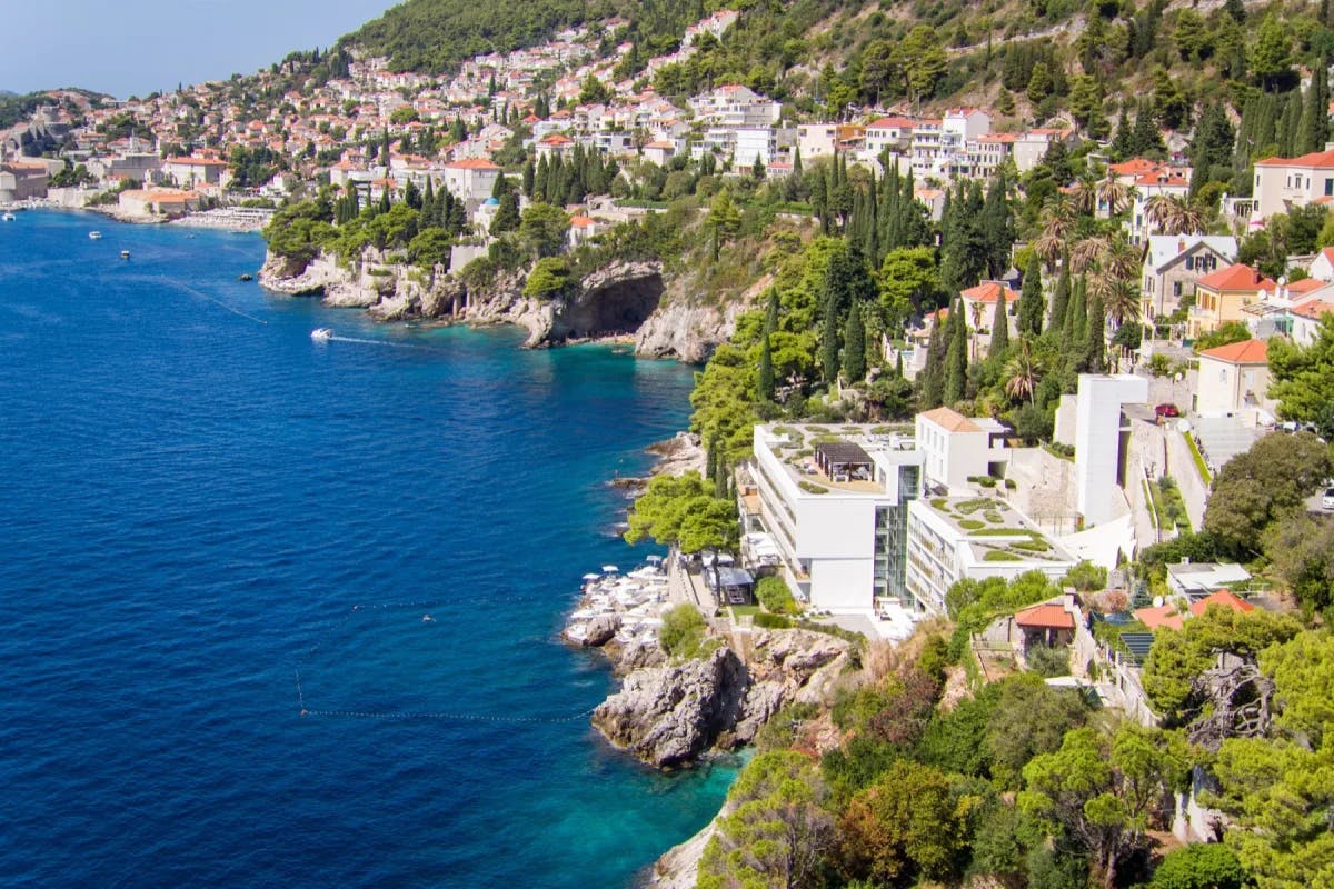 wide shot of the Croatian coastline with turquoise sea, cliffs and red-roofed buildings