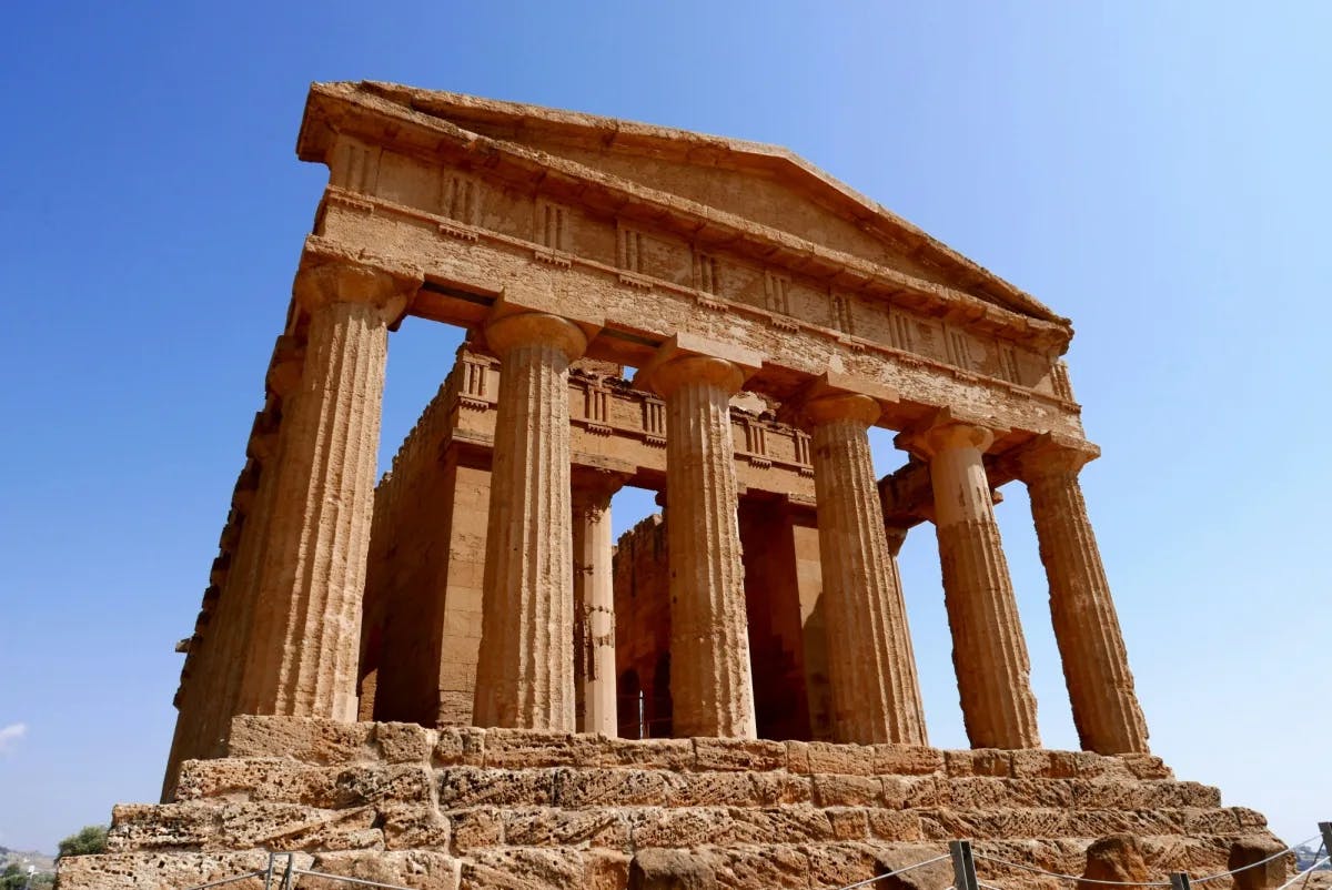 Ruin of a temple with pillars on top of stone steps.