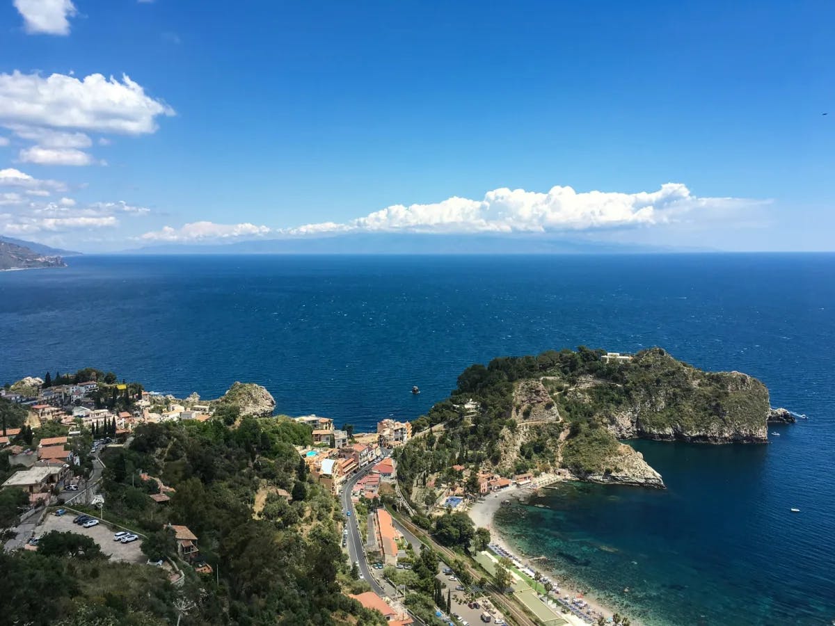 Aerial view of city along a coastline with a rocky outcropping.