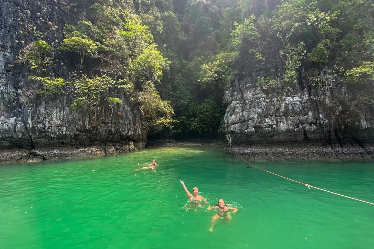 Isabel and friends swimming in green water next to rock formations at Phi Phi Islands