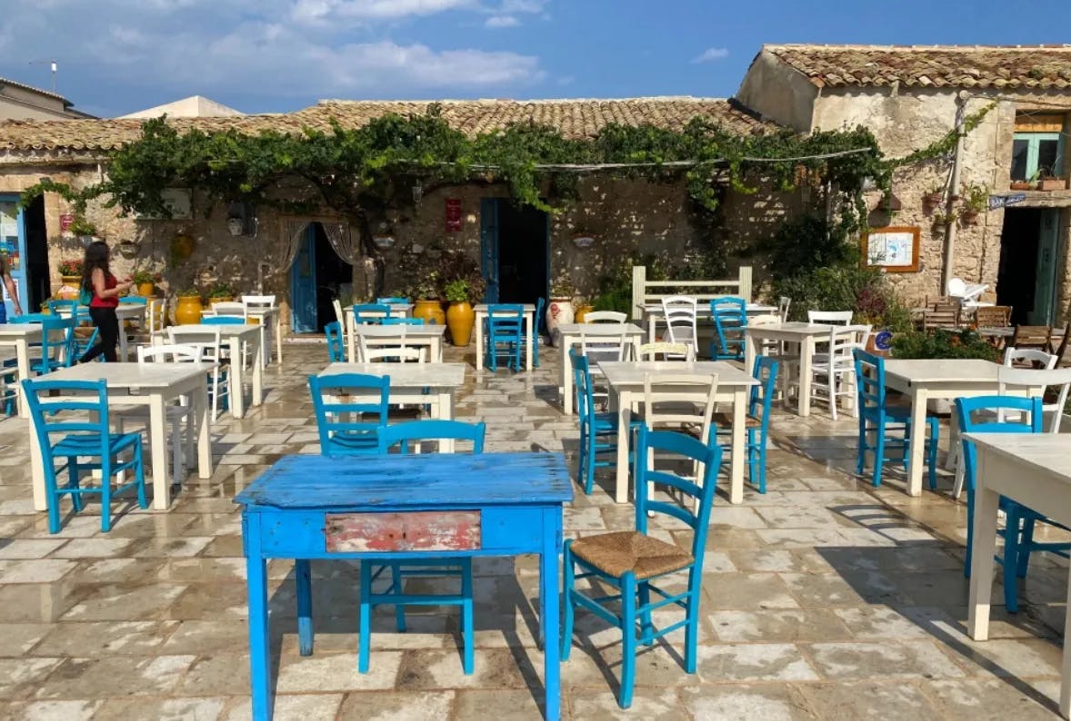 A pretty outdoor restaurant with blue and white tables in a couryard.