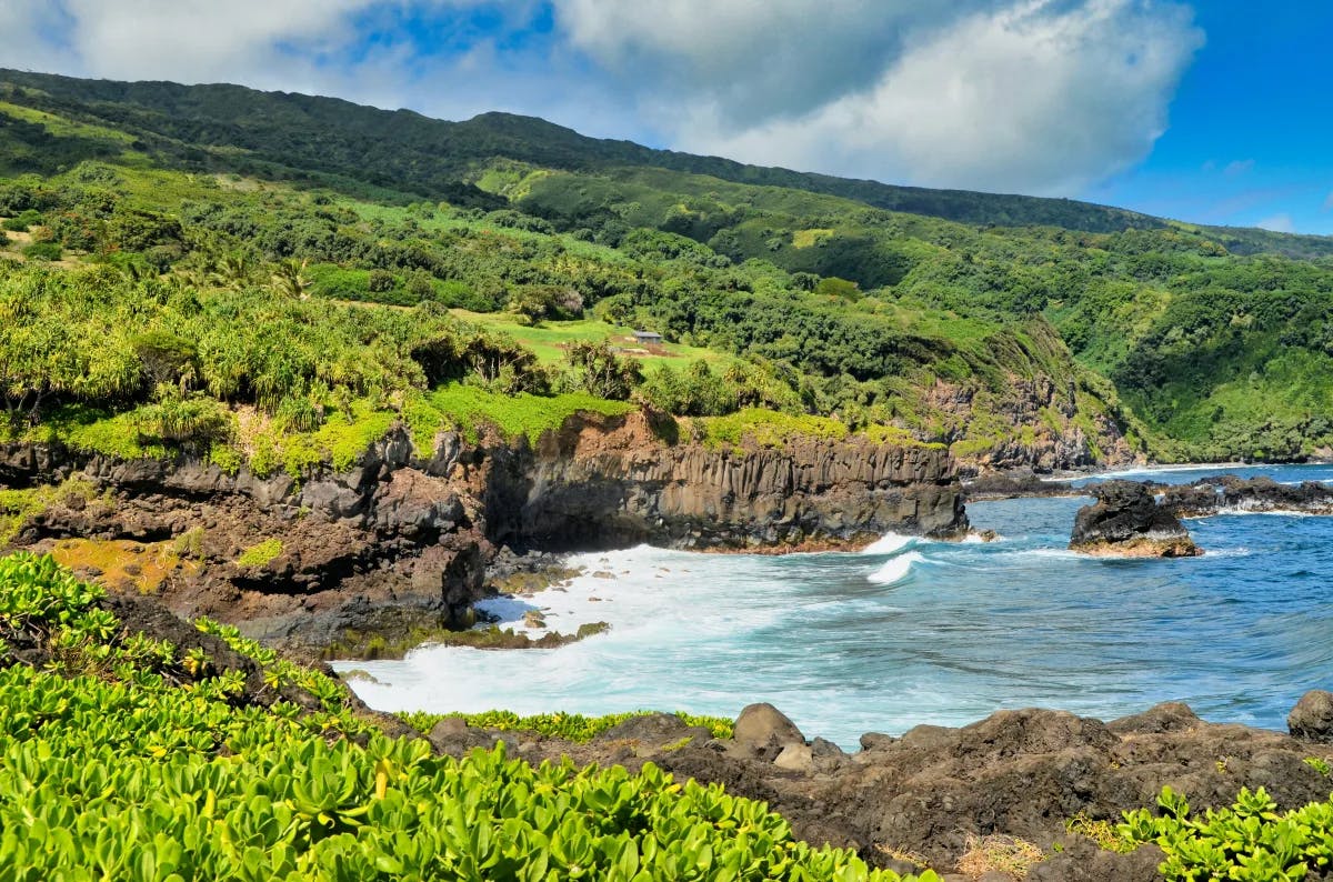 Body of water next to cliffs and green mountains during daytime