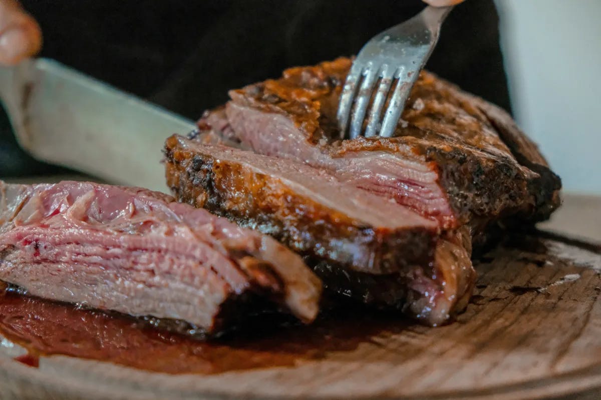 A person cutting a thick, juicy steak on a plate.