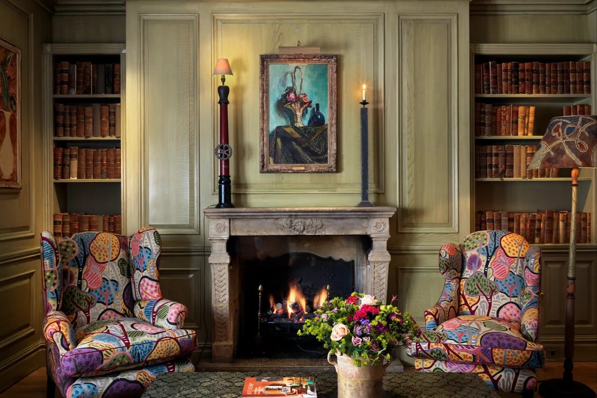 two vibrantly patterned upholstered arm chairs in front of a stone fireplace