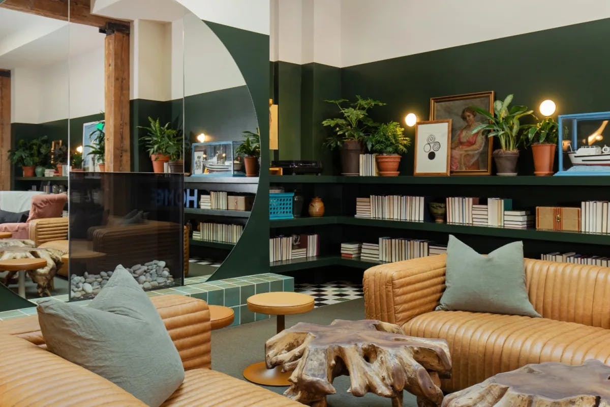 leather couches in a green room with a big round mirror