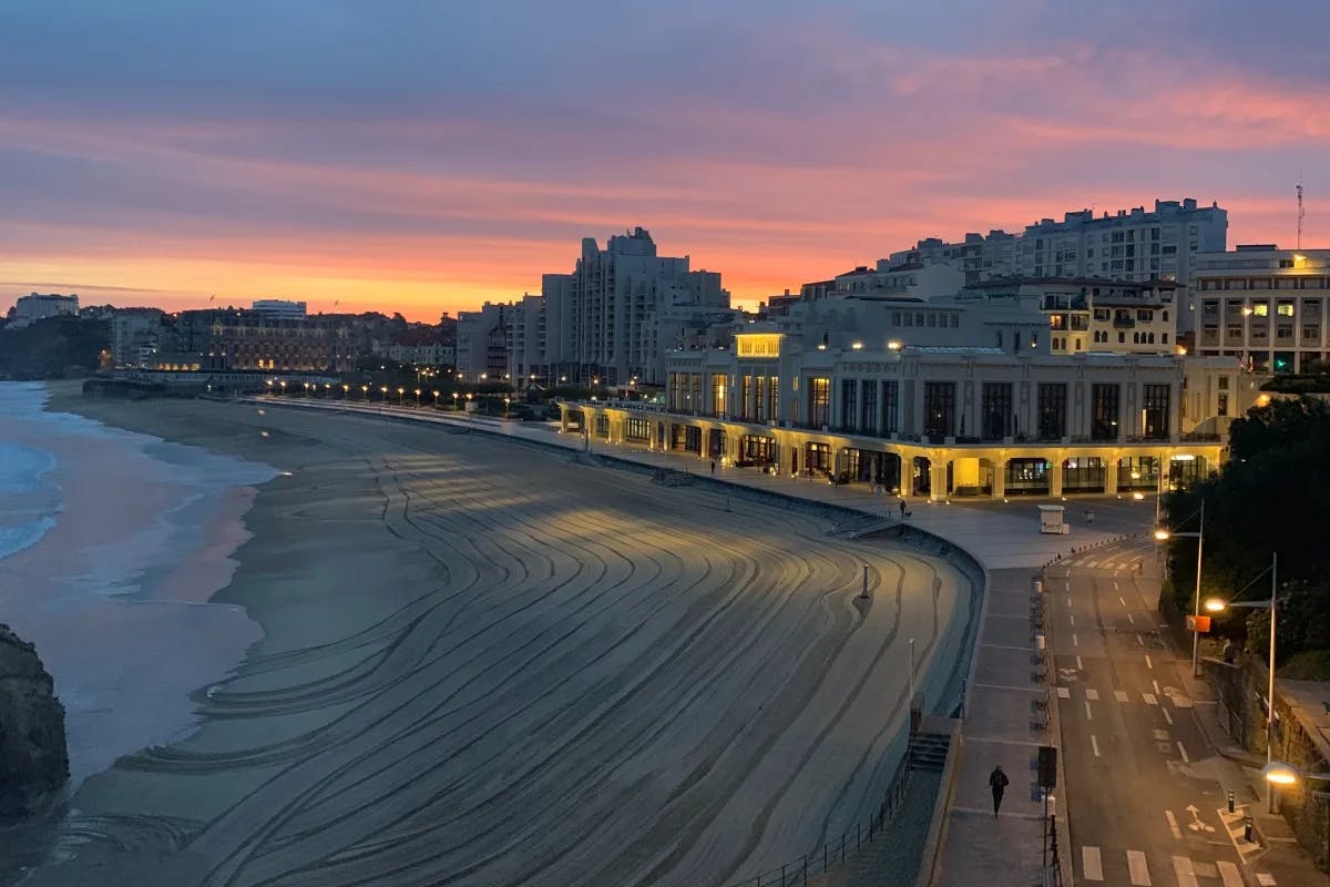 View of Grande Plage at sunset, with city buildings next to the beach. 