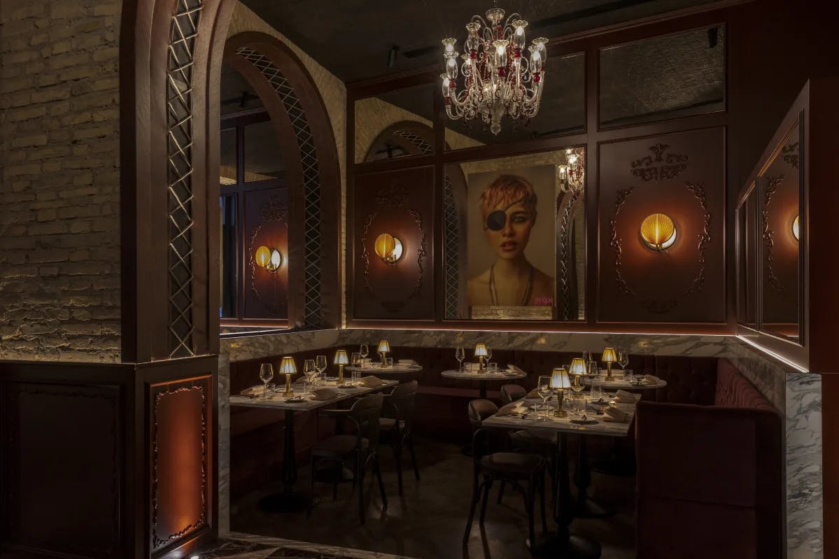 A wood-paneled restaurant with an intricate chandelier and a painting of a woman with an eye patch on the wall.