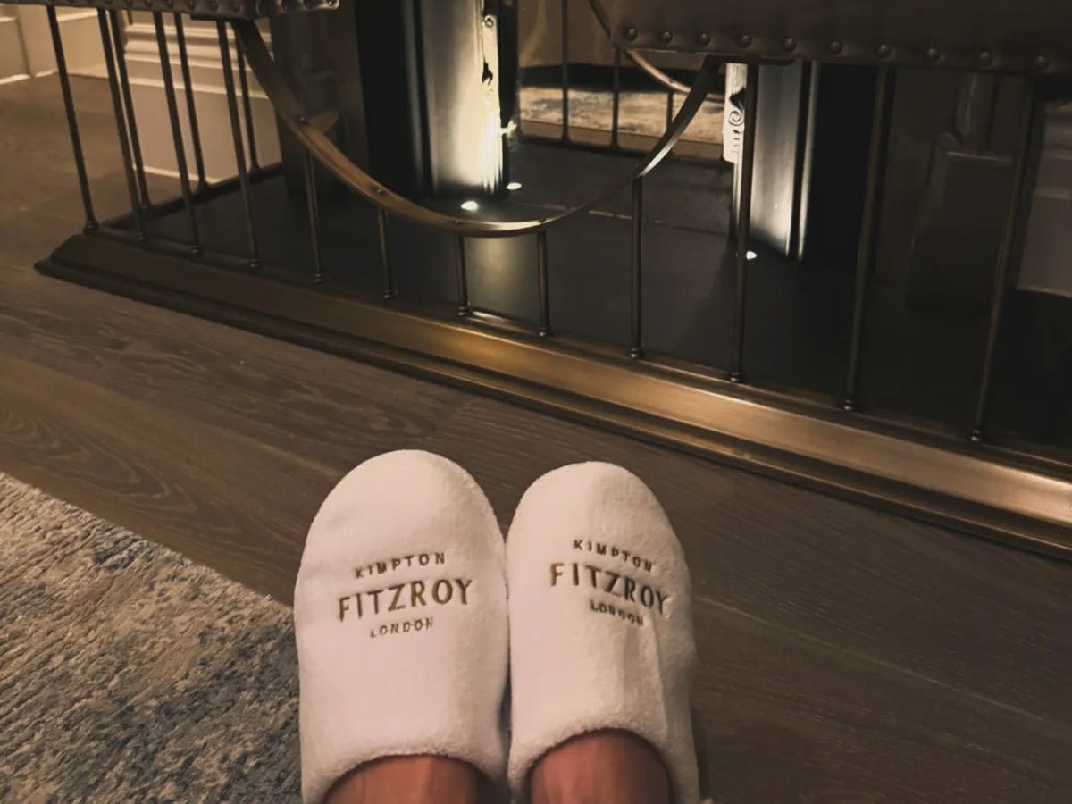 A picture of a person's feet, wearing hotel slippers.