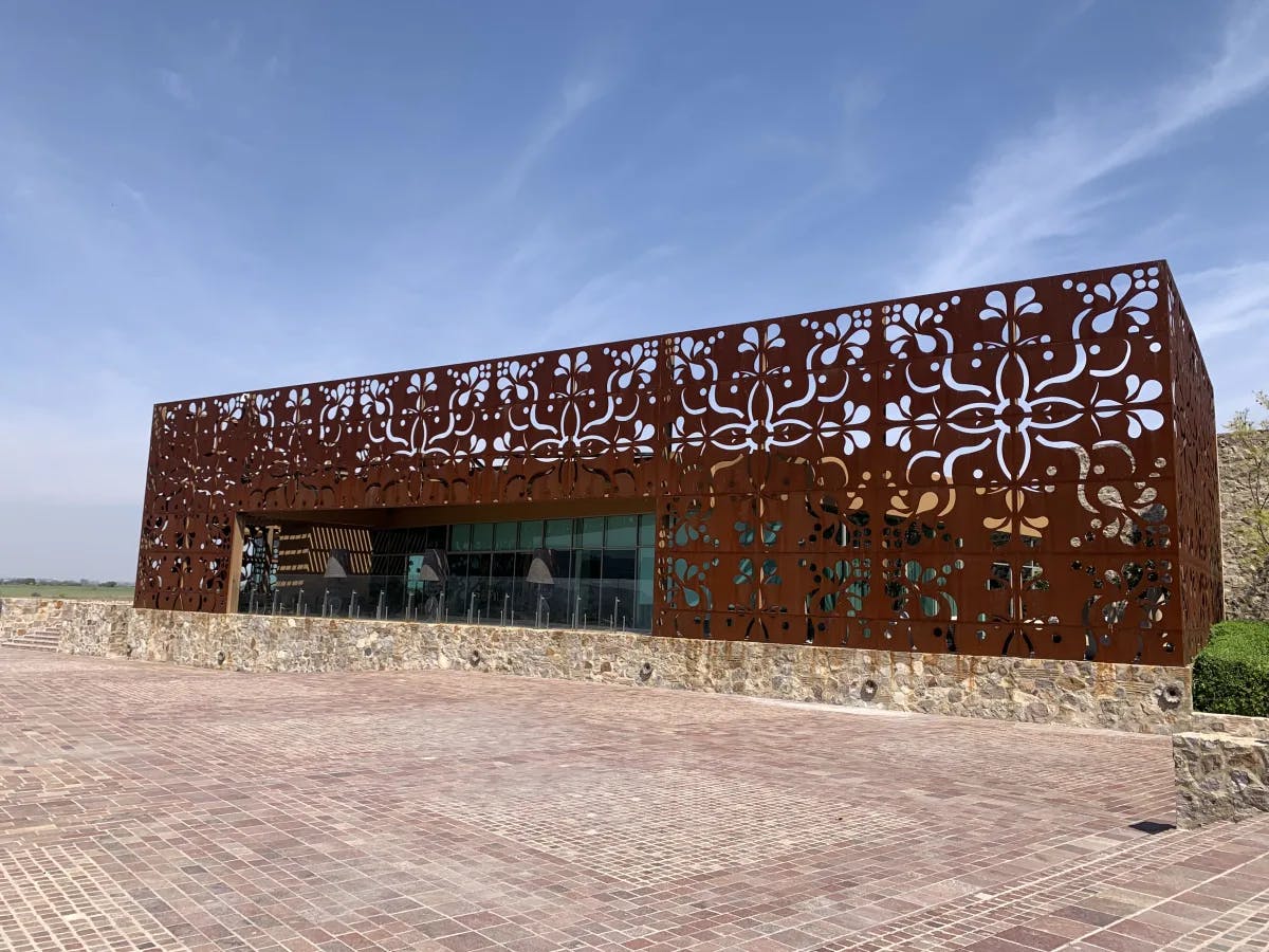 A view of the rectangular facade of a winery with unique corten steel design in a rust color