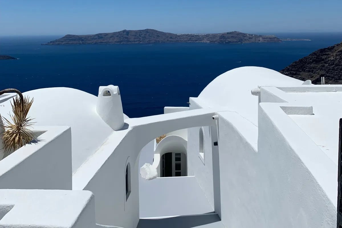 An iconic white Greek building with blue water in the background.