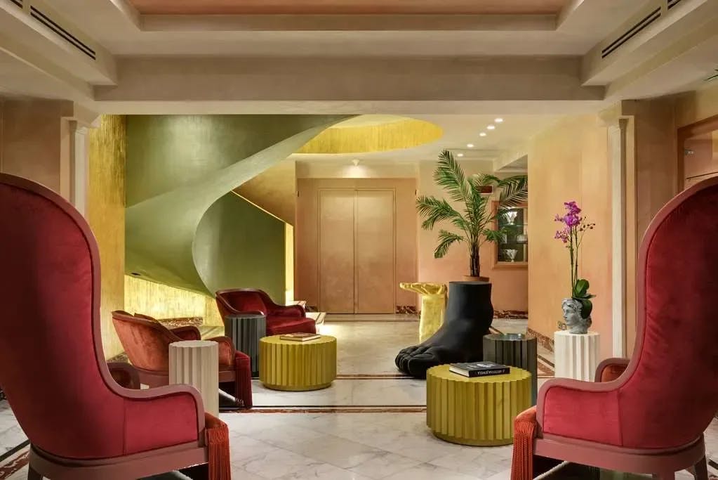 large red velvet chairs in a foyer with a giant foot serving as a planter