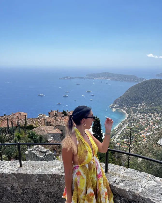 Samar Asfour posing by a suspended view of the ocean with boats.