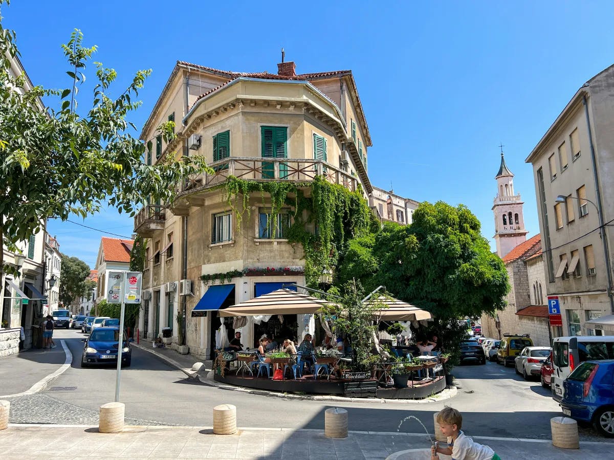 A low angled shot of the street with a building in the middle, joining two roads.