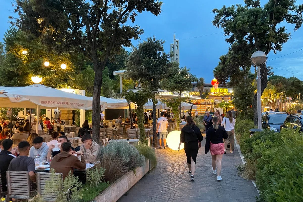 A picture of an outdoor setting where people are dining, walking enjoying in the open air.