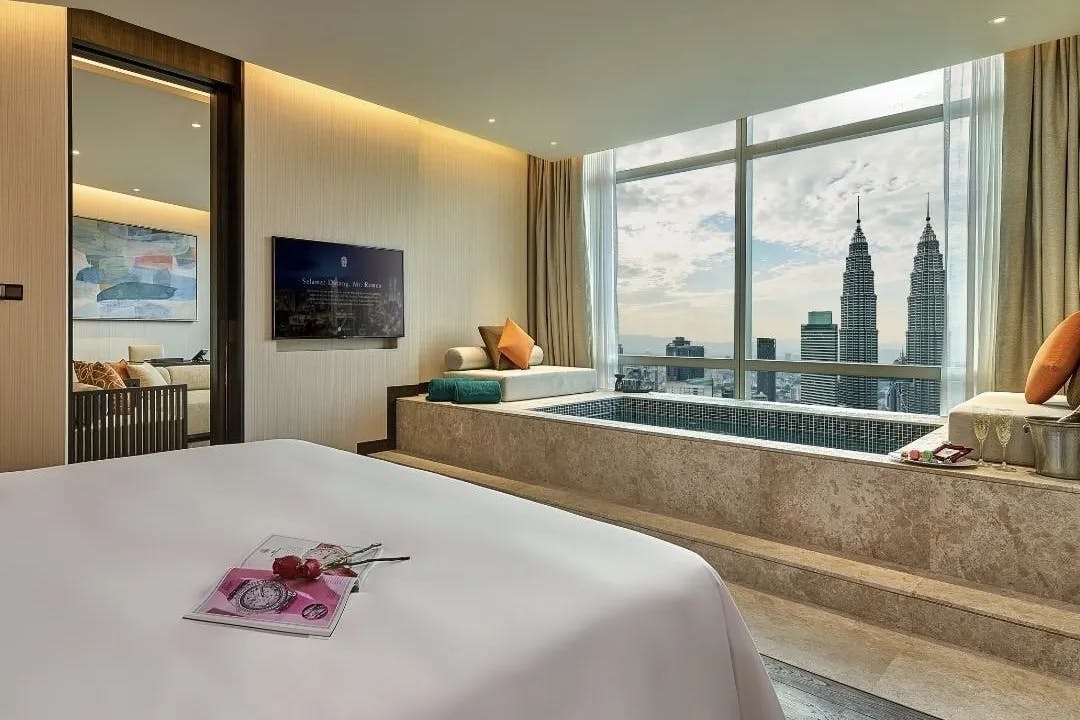 A hotel room with a city skyline view through the windows