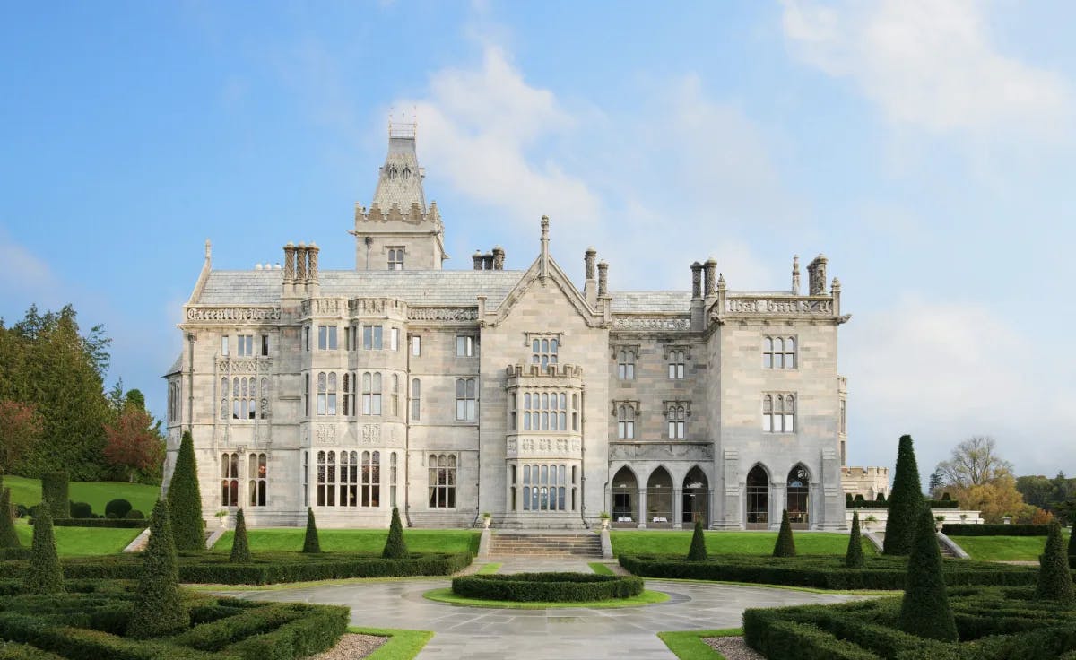 The exterior of Adare Manor, an impressive stone building set on manicured lawns.