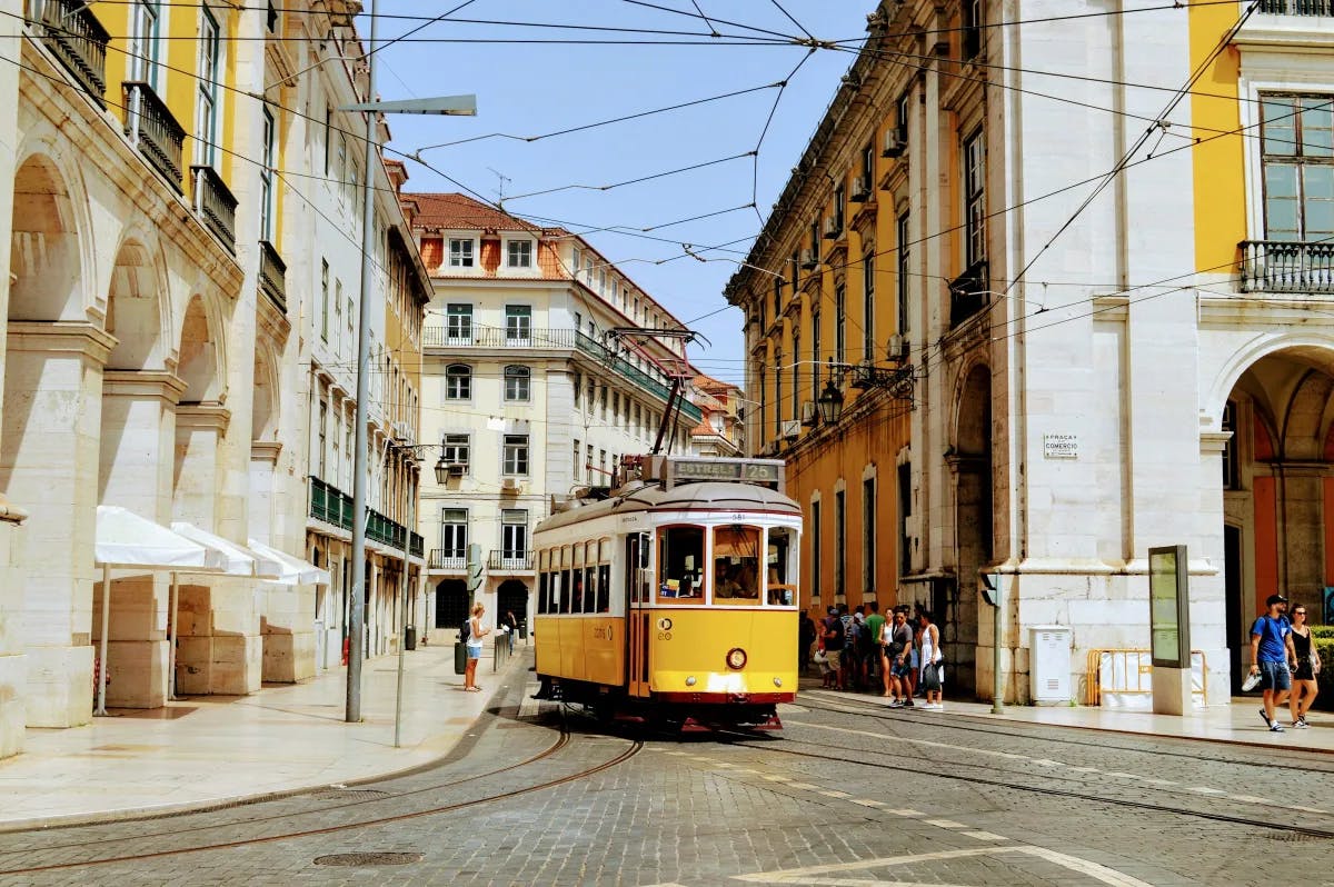 A yellow trolley and local architecture on a small road of Lisbon.