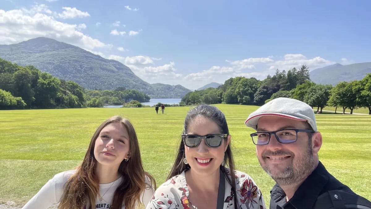 A family standing on a green field with lake at the background.