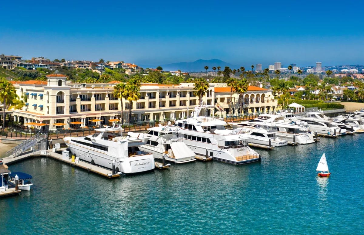 white yachts dock in a bay in front of a large hotel