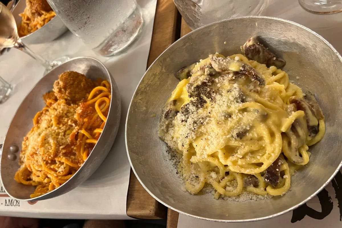 A picture of pasta served with a glass of wine on a table.