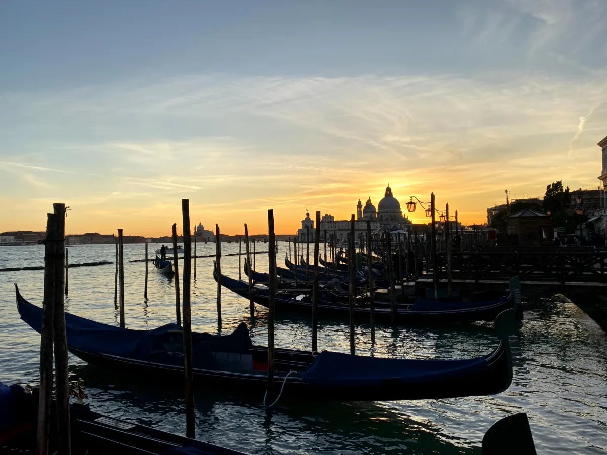 A picture of Venetian Gondolas anchored near the docks during the sunset.