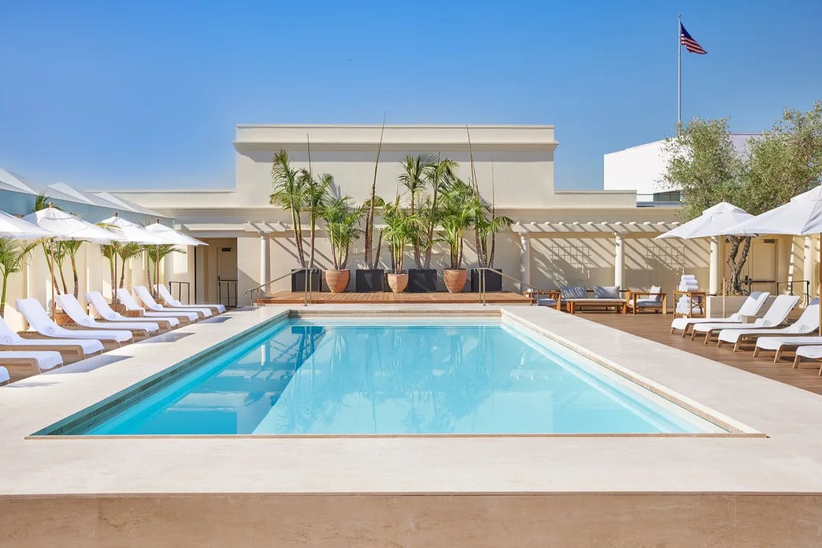 rooftop pool flanked by white loungers under a blue sky