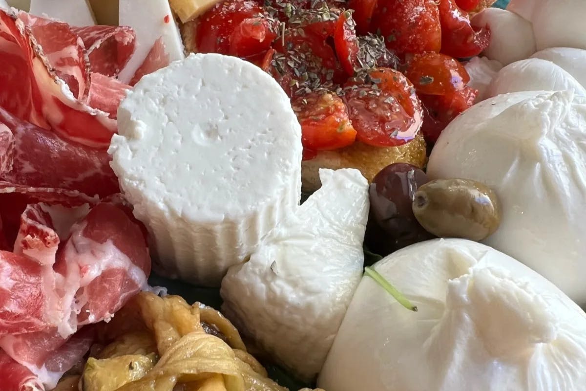 A plate of various cheeses, meats, and fruit